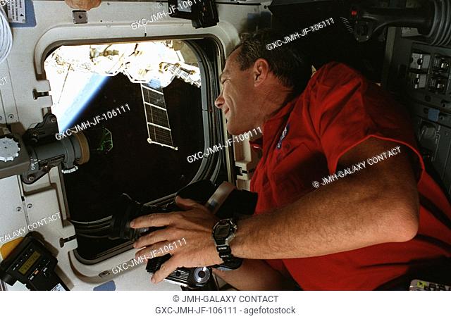 Astronaut Terrence W. Wilcutt, on the Space Shuttle Atlantis' aft flight deck, takes pictures of Earth for study by Earth observations scientists at the Johnson...