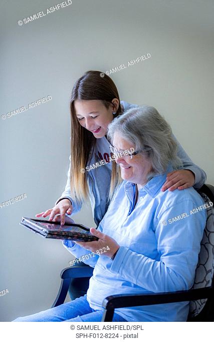 Teenage girl showing her grandmother how to use a digital tablet