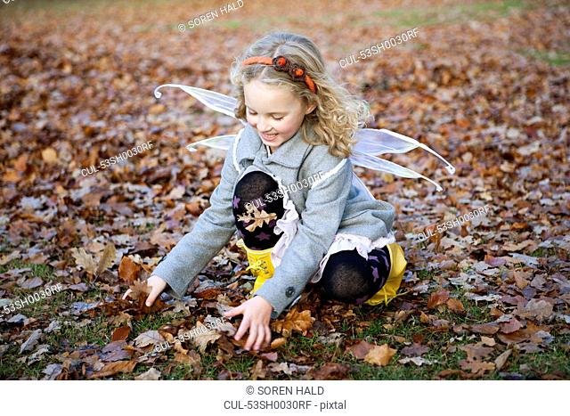 Girl in fairy wings playing in leaves