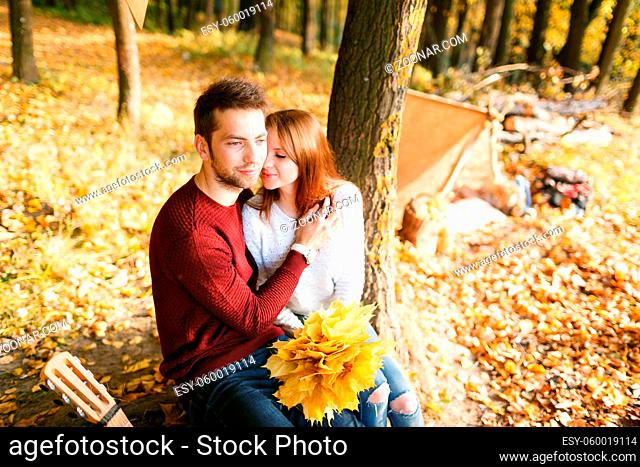 Happy couple with guitar near the tent. a hike in the woods