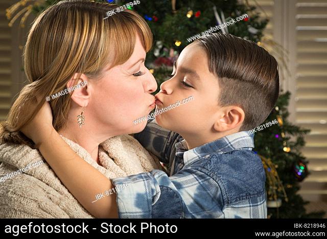 Happy mother and mixed-race son hug near their christmas tree