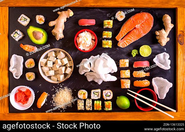 Set of traditional japanese food on a dark background. Sushi rolls, nigiri, raw salmon steak, rice, cream cheese, avocado, lime, pickled ginger (gari)