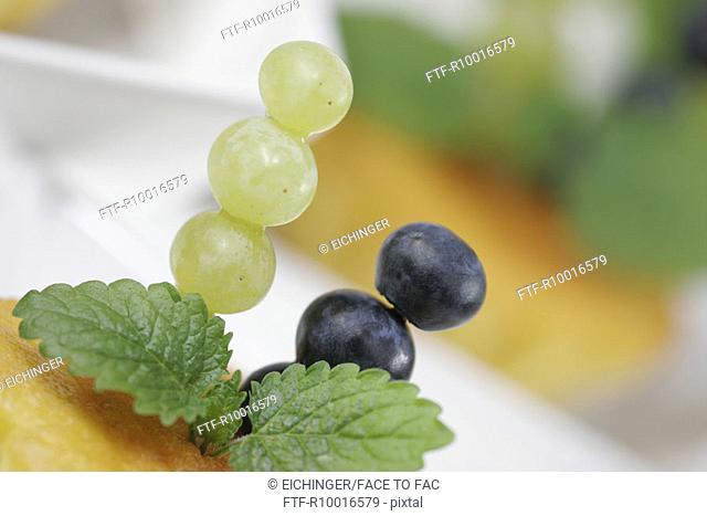 Piece of pineapple is garnished with grapes and leaves