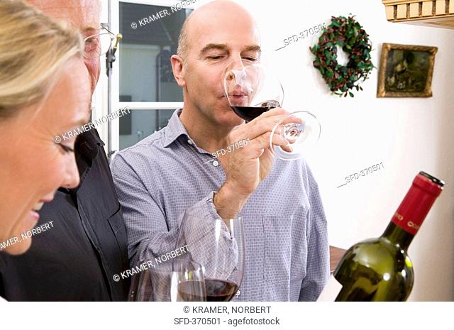 A woman and two men tasting red wine