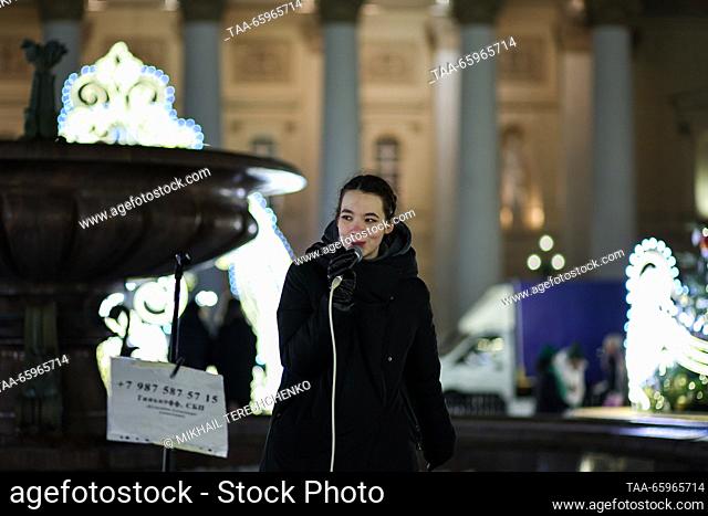 RUSSIA, MOSCOW - 21 de diciembre de 2023: Una mujer canta en la plaza Teatralnaya adornada con luces navideñas. Mikhail Tereshchenko/TASS