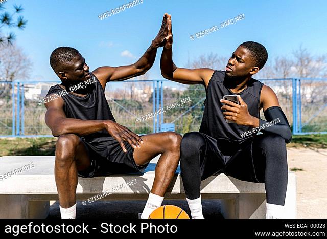 Basketball players high-fiving on outdoor basketball court