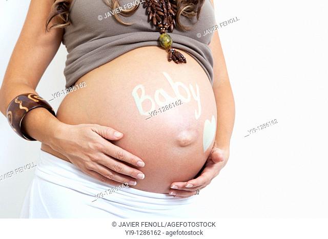 Pregnant woman holding her swollen abdomen