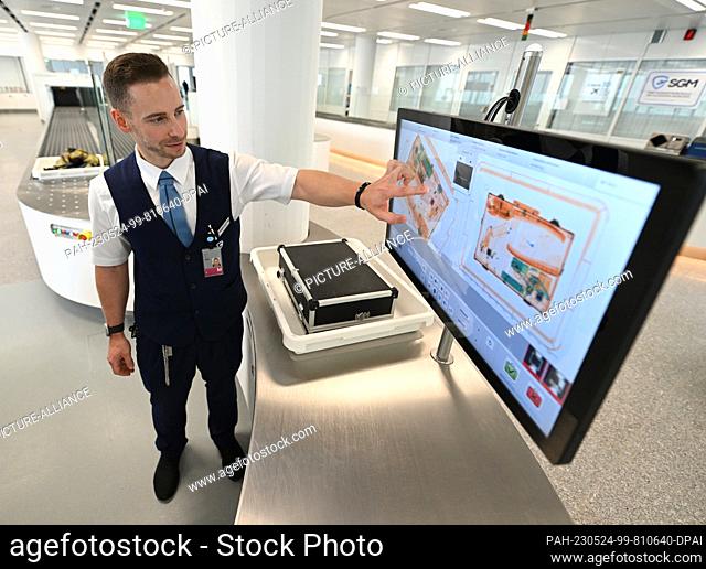 24 May 2023, Bavaria, Munich: ILLUSTRATION - A security checkpoint employee checks a piece of luggage in one of a total of five new installations at Munich...