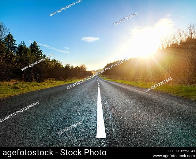 View along straight country road in Ulster, Northern Ireland at sunset