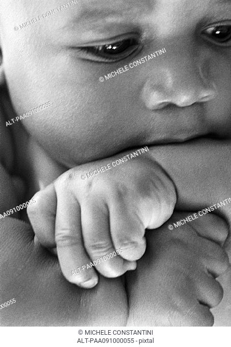 Baby with arm in mouth, close-up, b&w