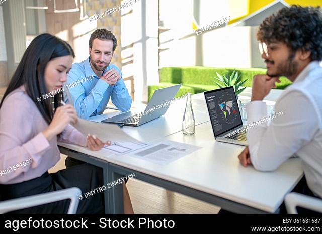 Business team. Two men and woman working in the office and looking involved