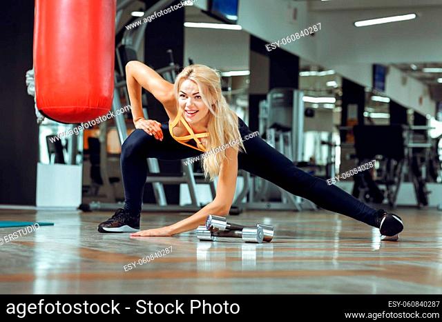 Young slender blond woman doing exercises in a gym