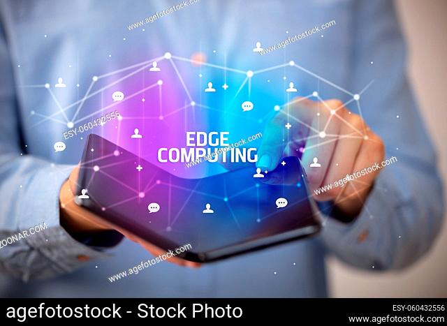 Businessman holding a foldable smartphone with EDGE COMPUTING inscription, new technology concept
