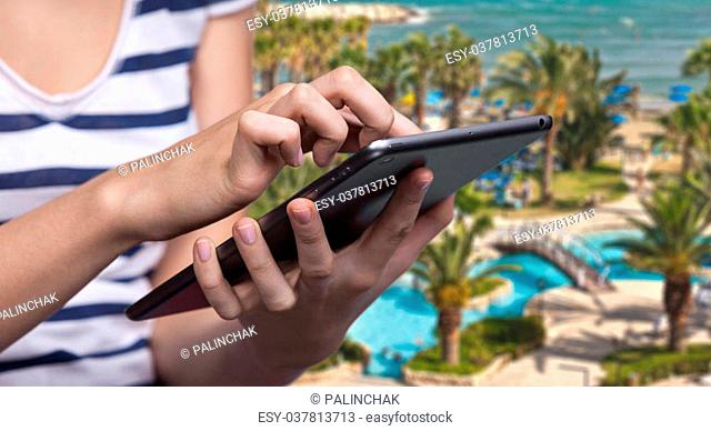Summer vacation and online booking. Hotel reservation via Internet. Young woman uses a tablet PC for hotel reservation