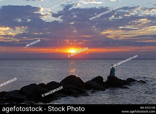 Woman sitting on stones, sunset, Steinbeck, Klütz, Mecklenburg-Western Pomerania, Germany, Europe