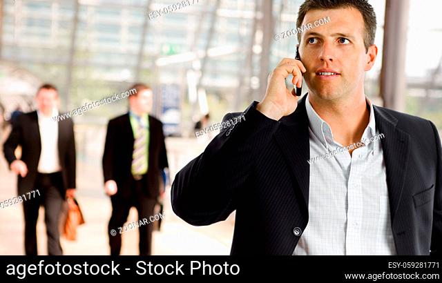 Businessman walking at office lobby talking on mobile phone