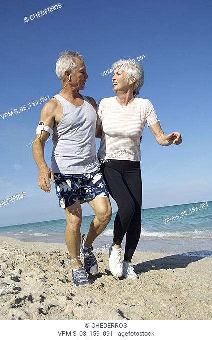 Senior couple walking on the beach and looking at each other