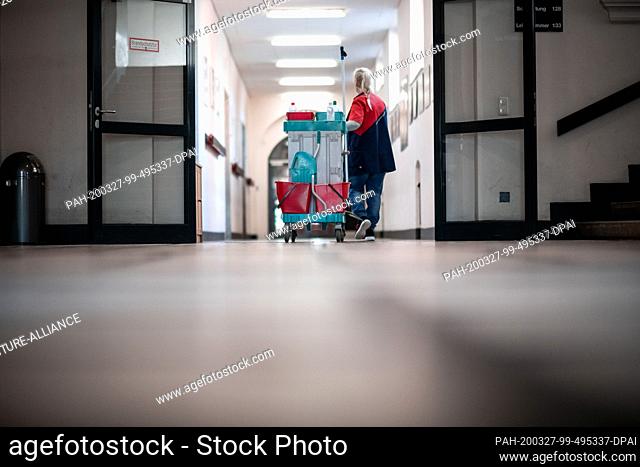 27 March 2020, North Rhine-Westphalia, Oberhausen: The cleaner Jutta Ochss-Brück walks along an empty school corridor with a cart