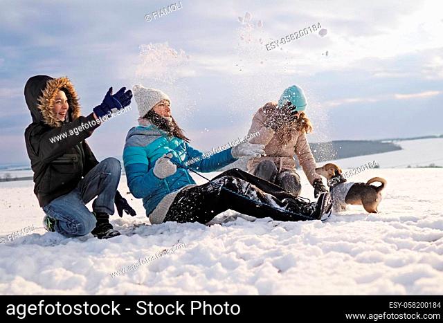 family walks the small dog in woolen clothes in the snow during winter time