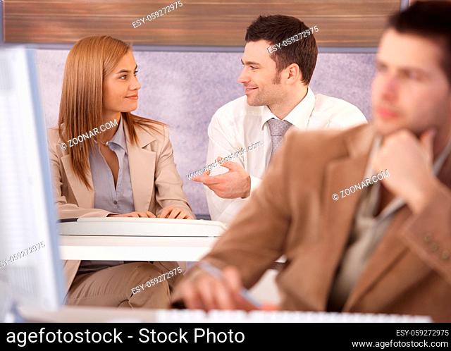 Attractive young woman and man chatting at computer course