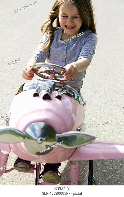 Smiling girl driving toy airplane