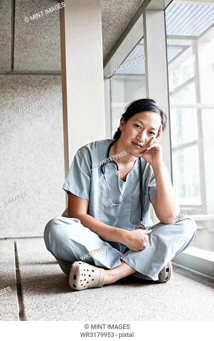 Asian woman doctor in scrubs in a hospital hallway