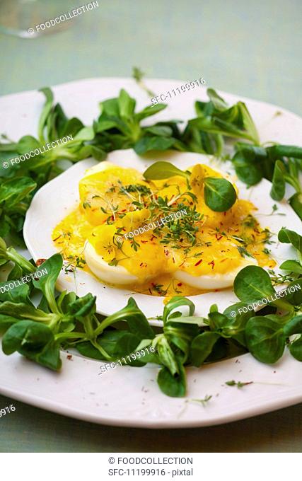 Halved boiled eggs with mayonnaise and cheese sauce, garnished with lamb's lettuce, saffron and cress