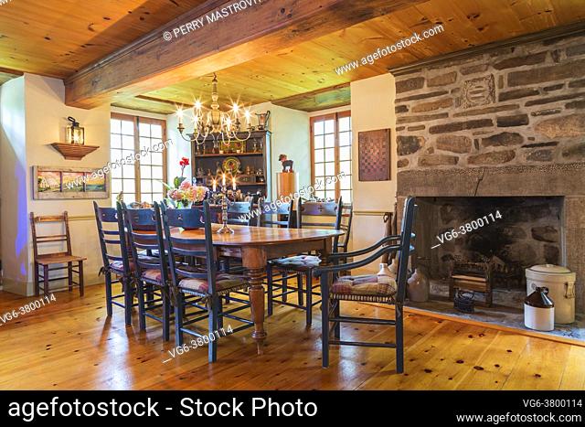 Pine wood dining table with two captain's armchairs and six high back chairs, antique pine wood buffet and natural stone wood burning fireplace in dining room...