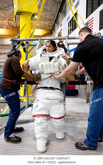NASA astronaut Sunita Williams, Expedition 32 flight engineer and Expedition 33 commander, gets help donning a training version of her Extravehicular Mobility...