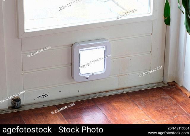 Inside view of a regular white cat flap on a light door, flap closed
