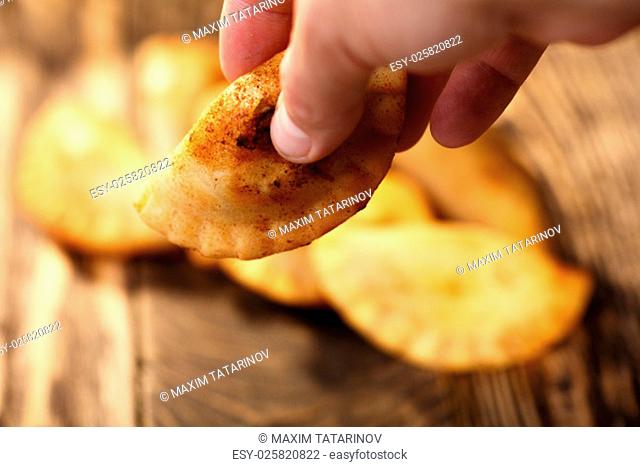 Male hand holding fried colombian empanada. Savory stuffed patties also known as pastel, pate or pirozhki