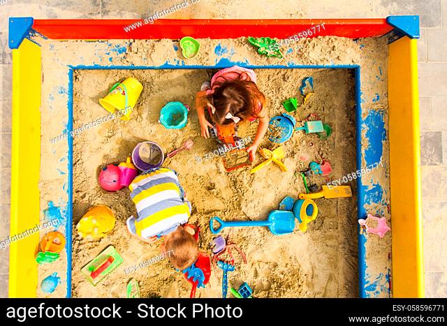 Top view of kids games in the sandbox. Boy and girl play at the playground. Concept of creations, coloufrul toys