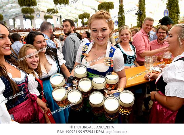 21 September 2019, Bavaria, Munich: Start of the Oktoberfest. The Wiesnbedienung Beli carries the first beer mugs to the guests in the Hofbräuzelt