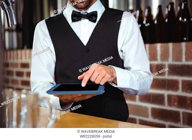 Handsome barman using tablet computer