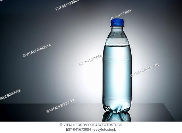 Plastic bottle with water. Gradient background. Mirror reflection