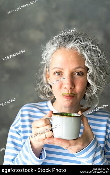 Woman with matcha tea mustache holding cup