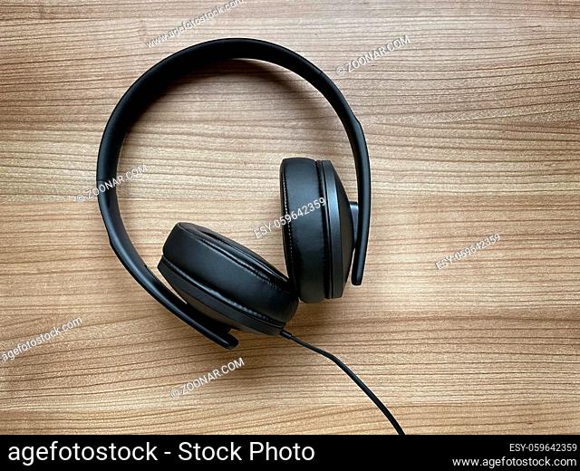 pair of black around-ear or over-ear headphones lying on wooden desk