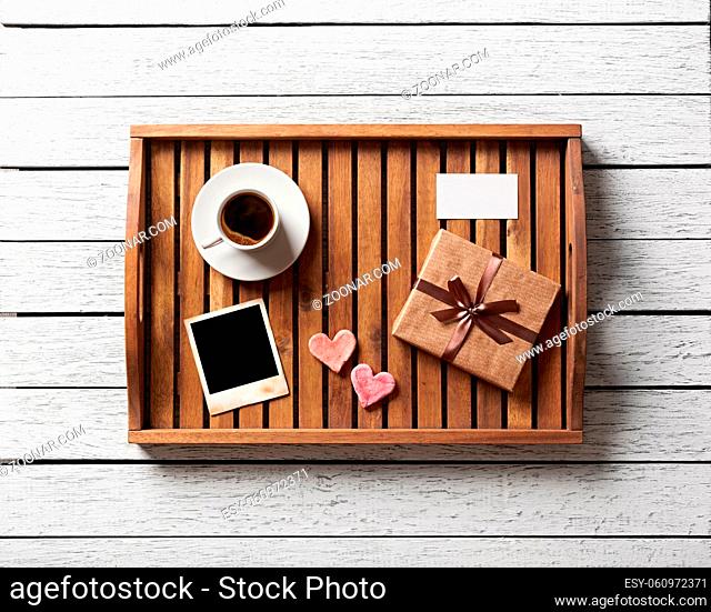 Photo frame and hearts and gift box with cup of coffee on wood