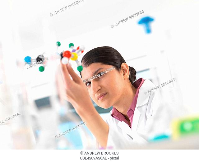 Female scientist in laboratory, viewing molecular model of a chemical formula