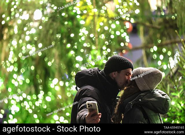 RUSSIA, ST PETERSBURG - DECEMBER 20, 2023: A young couple share a kiss during a ceremony to light up the main Christmas tree of St Petersburg in Palace Square