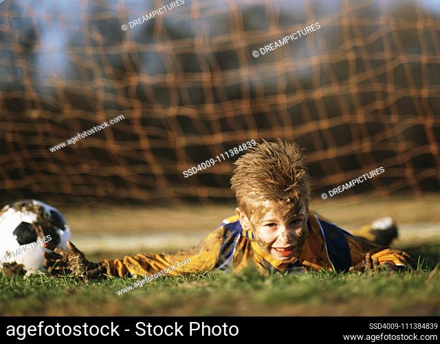 Boy covered in mud with soccer ball