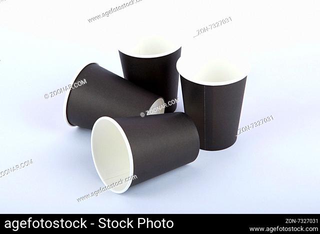 Close up detailed top view of four recycled black lying and standing paper glasses, isolated on white background