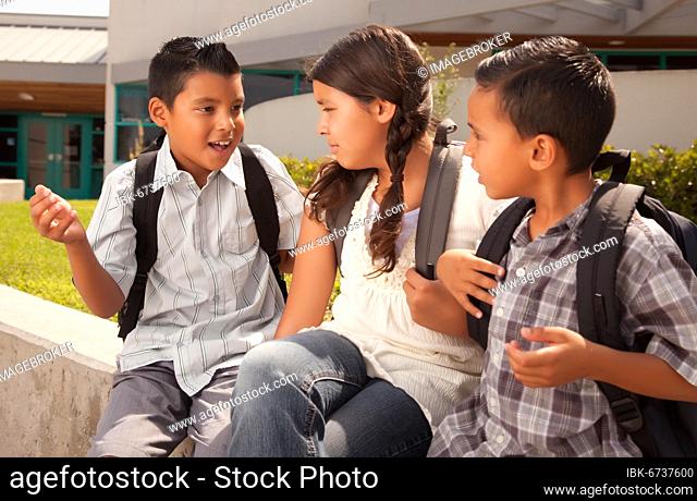 Cute brothers and sister wearing backpacks ready for school