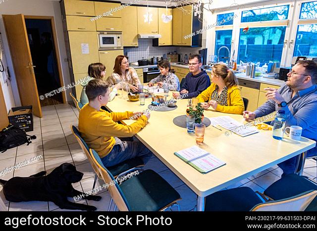 PRODUCTION - 12 January 2023, Mecklenburg-Western Pomerania, Wolgast: Nadine and Jörg Deutschmann sit with some of the children at the large table in the...