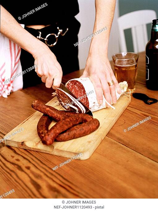 Woman cutting sausage on chopping board