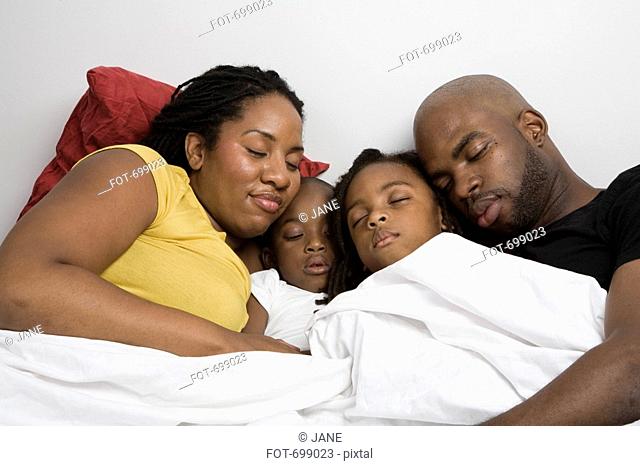 A family four sleeping in bed together