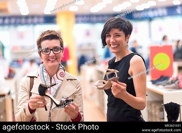 Two Girl-Friends On Shopping Walk On Shopping Centre With Bags And Choosing