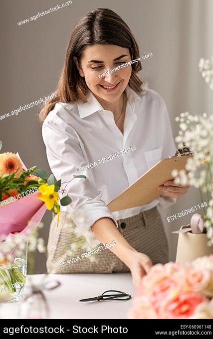 happy woman with clipboard and flowers at studio