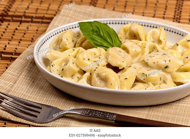 Italian tortellini pasta with cheese sauce and basil. Selective focus