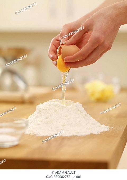 Woman cracking egg over flour nest